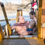 A father holding one of his two son in the Moscow River during Epiphany.