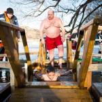 A Russian father watching his son dip into the cold Moscow River during Epiphany celebration.