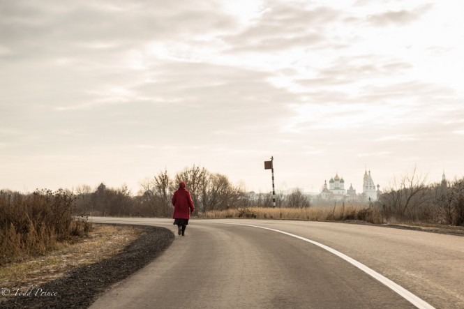 A woman in red walking back toward Kolomna from the Bobrenev Monastery. Kolomna’s churches can be seen in the distance.