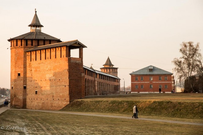 People walk by the the Kolomna Kremlin wall at sunset.