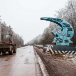 Heavy machinery passes a Soviet emblem welcoming people to one of Russia's largest iron ore mines.