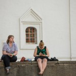 Two girls sitting in front of a church on New Arbat street on a Friday summer evening.
