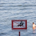 A Russian man bathing near a sign that says 'No Bathing.'