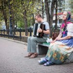 An elderly woman belts out Soviet songs as her son plays the accordion.
