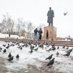 Migrant workers photographing pigeons in front of the Lenin statue in Yuzhno-Sakhalinsk.