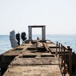 A Russian boy sitting at the edge of an old pier in Sochi.