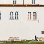 A worker walking by a church wall in the late afternoon.