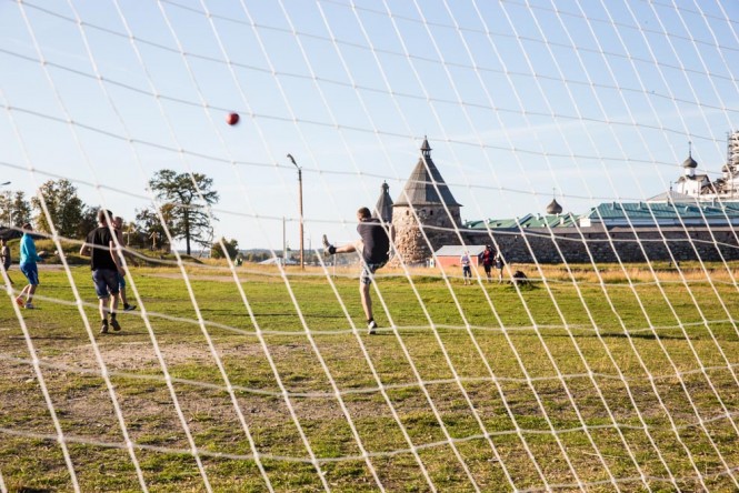 The goal keeper, a construction worker during weekdays, kicking a soccer ball near the Solovetsky Monastery.